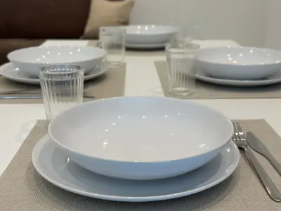 a white plate on a table with glasses and forks at Lily Suite 10 in Palermo
