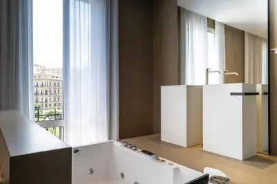 a bathroom with a white tub and a large window at Amorgiù Luxury Suites in Palermo