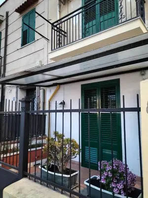 a house with green doors and potted plants at Ciuridda mia in Palermo