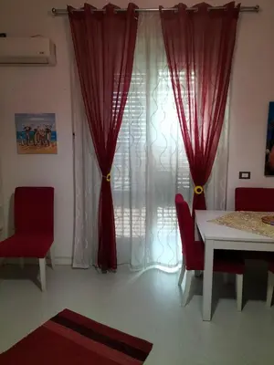 a dining room with a table and red chairs and a window at Ciuridda mia in Palermo