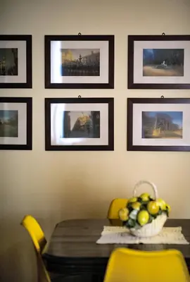 a dining room table with yellow chairs and pictures on the wall at la Kalsa 14 nel centro storico di Palermo in Palermo
