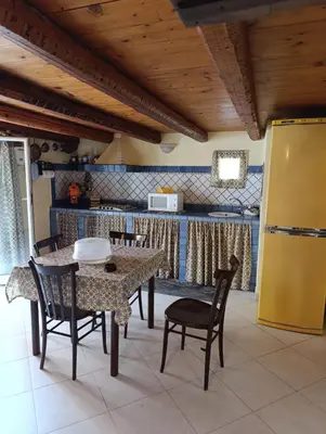 a dining room with a table and chairs and a kitchen at Maison al-Aziz in Palermo