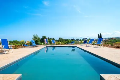 a swimming pool with blue chairs at Villa Maguetta with private pool in Scopello in Scopello