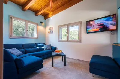 a living room with a blue couch and a flat screen tv at Villa Maguetta with private pool in Scopello in Scopello