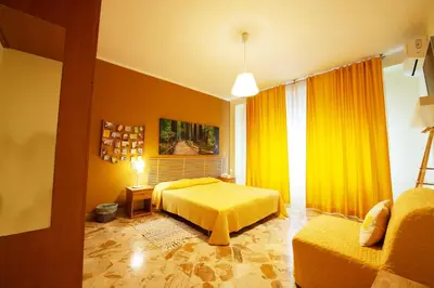 a yellow bedroom with a bed and a couch at La Favorita - Ben collegato con l'aeroporto, la spiaggia di Mondello e il centro città in Palermo
