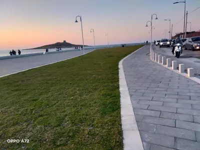 a sidewalk next to the beach with cars and a motorcycle at Casa Vacanza Zá Cicciuzza in Isola delle Femmine