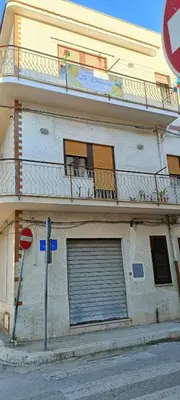 a building with a garage door and a balcony at Casa Vacanza Zá Cicciuzza in Isola delle Femmine