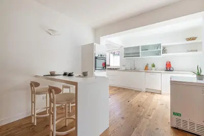 a white kitchen with wooden floors and white cabinets at Villa Nika in Palermo