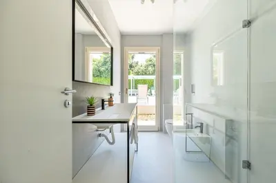a white bathroom with a sink and a glass door at Villa Nika in Palermo