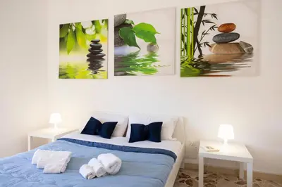 a bedroom with a bed with three paintings on the wall at STELLA BLU in Calatafimi