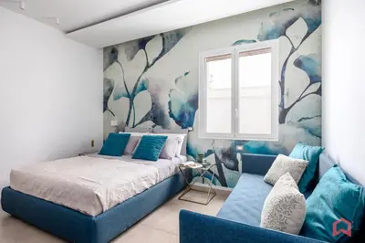 a bedroom with a bed and a blue couch at Appartamento in villa con piscina privata in Palermo