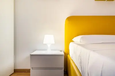 a bed with a yellow headboard and a lamp on a night stand at [MoroHouse] 50mt from Teatro Massimo in Palermo