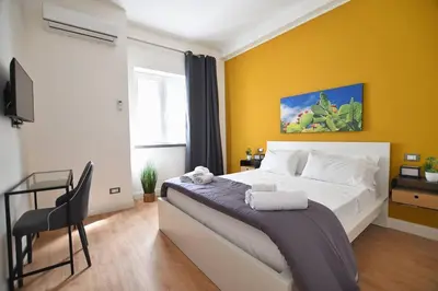 a bedroom with a large bed with a yellow wall at iFlat Normanni Lounge Apartment in Palermo