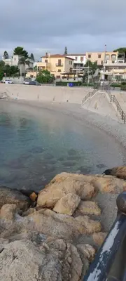 a beach with rocks in the water and buildings at Casa Vacanze Deianira in Santa Flavia