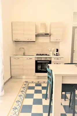 a kitchen with white cabinets and a table and a stove at Casa Vacanze Deianira in Santa Flavia