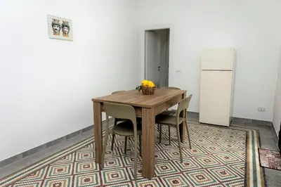 a dining room table with a bowl of fruit and a refrigerator at Casa Vacanze Altea in Santa Flavia
