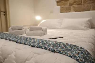 a large white bed with a patterned blanket on it at Casuzza palazzo storico, Stazione Centrale Palermo in Palermo