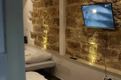 a room with a tv on a stone wall at Casuzza palazzo storico, Stazione Centrale Palermo in Palermo