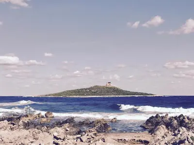 a small island in the ocean with a lighthouse on it at Casa sul Mare alle porte di Palermo in Isola delle Femmine