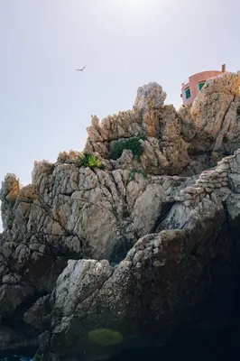 a rocky mountain with a building on top of it at Sant'Elia Luxury Home&Spa con accesso al mare in Santa Flavia