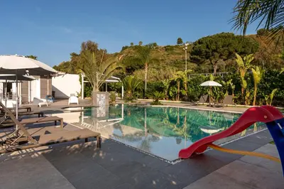 a swimming pool with palm trees and a house at Villa Solià - Villa indipendente con Piscina e Giardino in Campofelice di Roccella
