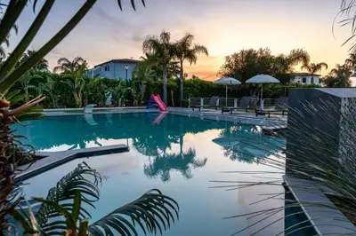 a swimming pool with white chairs and trees at Villa Solià - Villa indipendente con Piscina e Giardino in Campofelice di Roccella
