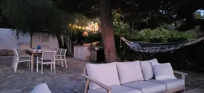 a white couch sitting on a patio with a table and chairs at Villa Ballerina Bianca in Scopello