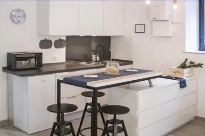 a kitchen with white cabinets and a counter with stools at Vuccirihouse in Palermo