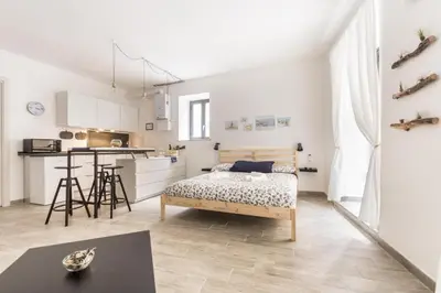 a white apartment with a bed and a kitchen at Vuccirihouse in Palermo
