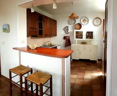 a kitchen with a counter with two stools and a sink at VILLA FLAMINIA - con piscina privata in San Vito lo Capo