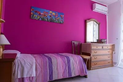 a bedroom with a purple wall with a bed and a dresser at CASA CRETTO in Salaparuta