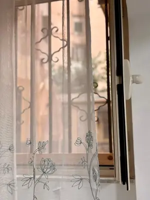 a window with a curtain with flowers on it at Casa vacanze La Bonta' di Palermo in Palermo