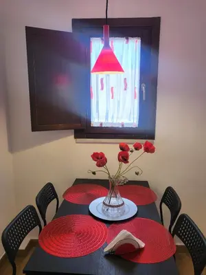 a table with red plates and a vase with red roses at Patrizia Chic in Palermo