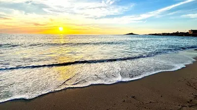 a beach with the sun rising over the ocean at Casa del Limone in Isola delle Femmine