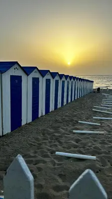 a row of blue and white beach huts on the beach at Casa del Limone in Isola delle Femmine