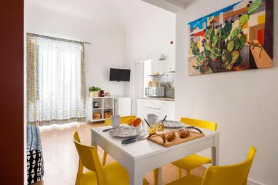 a dining room with a white table and yellow chairs at Agata & Rosalia 2 Suite Indipendenti e Comunicanti con Balcone & AC in Palermo