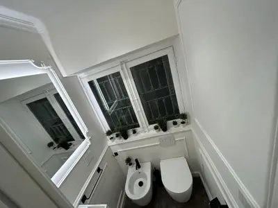 a small bathroom with a toilet and two windows at Maqueda view in Palermo