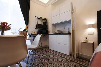 a room with a kitchen and a table with a counter at Maqueda view in Palermo