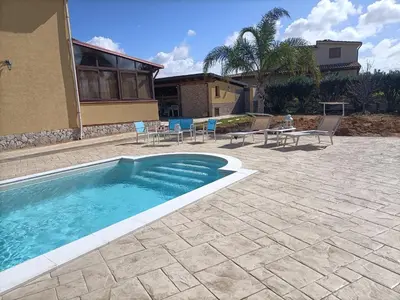 a swimming pool with chairs and a table and a house at Villa Panorama in Trappeto