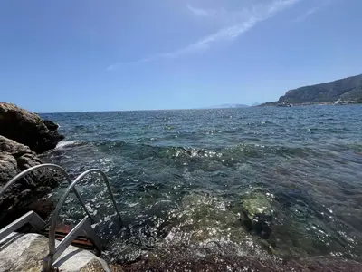 a boat in the water near a rocky shore at Ashur 163 - Mondello in Palermo