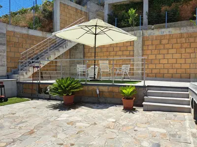 a patio with an umbrella and chairs and stairs at Villini AltaVista in Altavilla Milicia