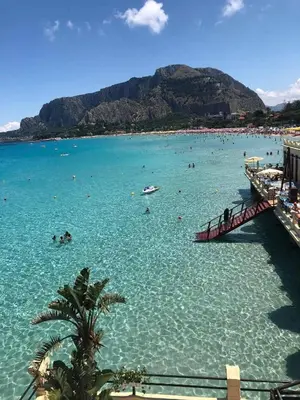 a beach with a bunch of people in the water at La casa di maretta,Mondello in Palermo