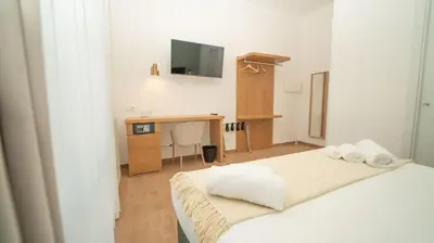 a room with two beds and a desk and a television at Manere Suites in Palermo