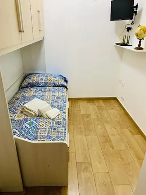 a small bed in a room with a wooden floor at Campofelice Happy Casa in Campofelice di Roccella