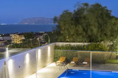 a balcony with a swimming pool and a view of the ocean at Villa Bizzarria in Castellammare del Golfo