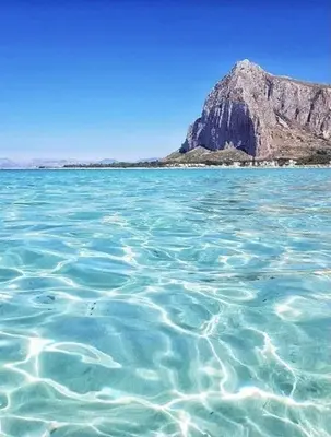 a large body of water with a mountain in the background at Calasole House: Mare a 2 Passi in San Vito lo Capo