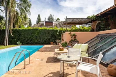 a patio with a table and chairs next to a swimming pool at Casa Mediterranea Attitudine By DomuSicily in Mondello