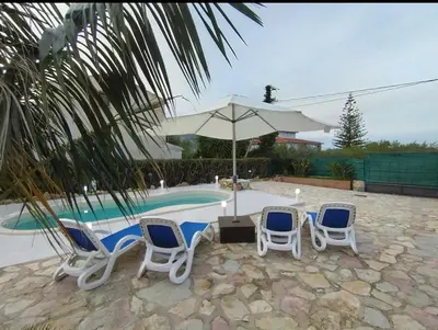 a group of chairs and an umbrella next to a pool at Villa Nuccia Oasi di relax con piscina in Castellammare del Golfo