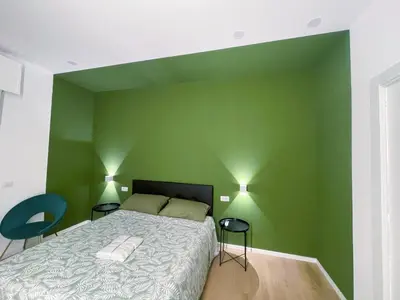 a green bedroom with a bed and two chairs at Central Empire in Palermo