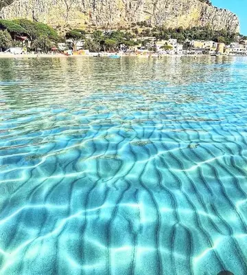 a large pool of water with a beach in the background at CasaRò (delizioso alloggio a Mondello) in Palermo